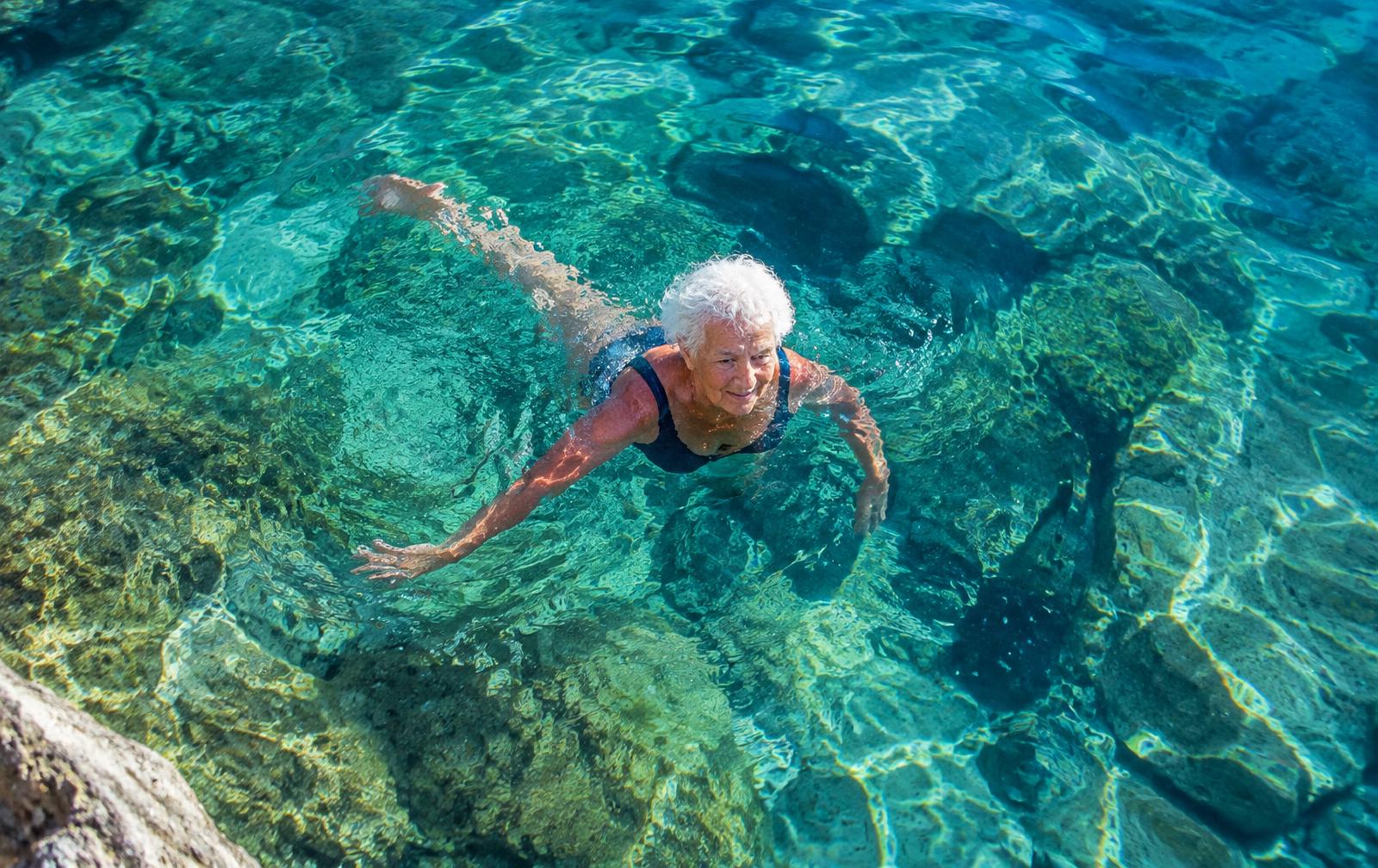 Una donna anziana nuota nel mare turchese del Mediterraneo